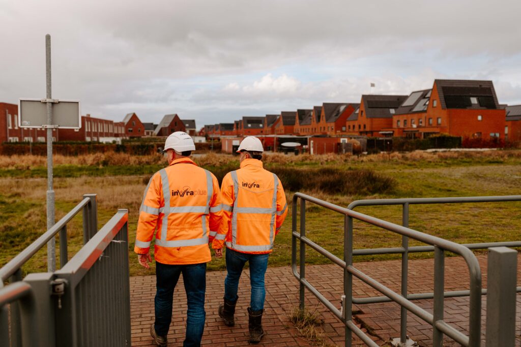Technisch manager civiele techniek van InVra plus in oranje veiligheidsvest in overleg op projectlocatie