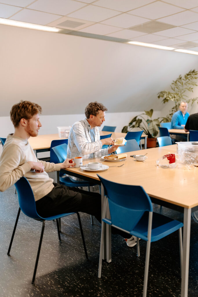 Kantinemedewerker verzorgt lunch voor het team bij InVra Plus, met een werknemer die geniet van een vers bereide maaltijd in de kantine.